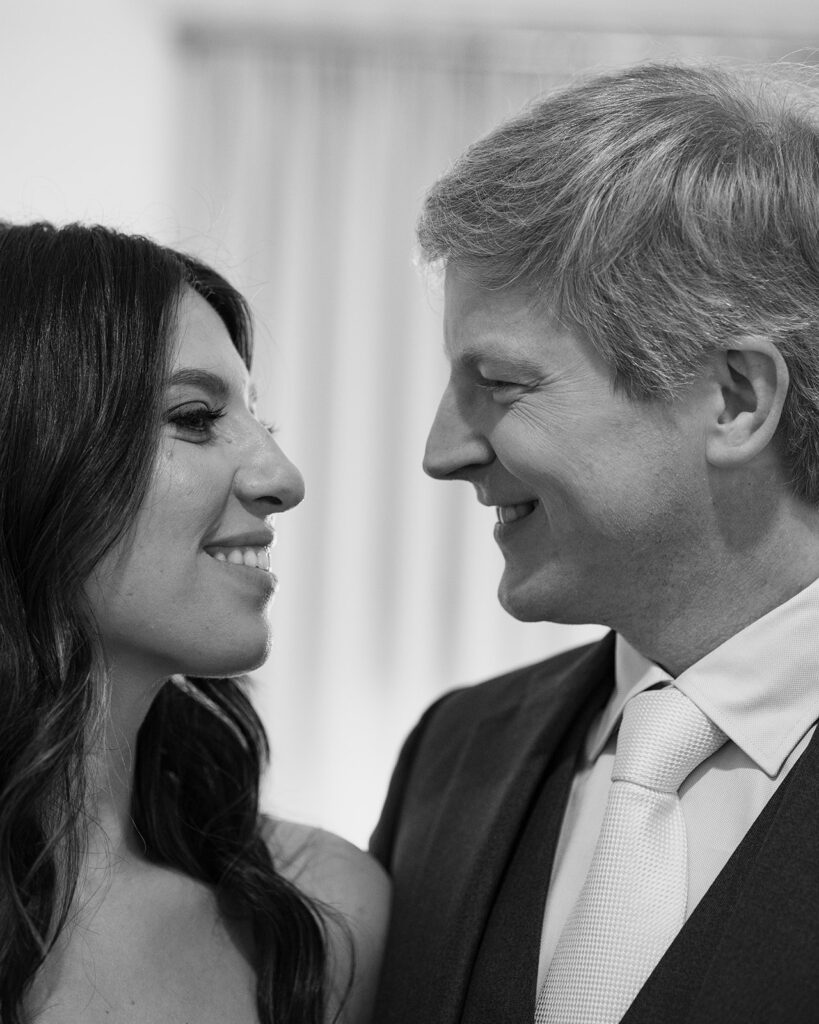 Black and white photo of a bride and groom smiling at each other