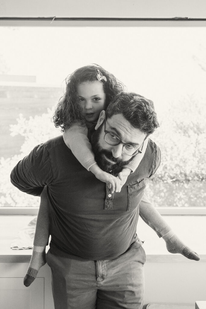 Black and white photo of a father giving his daughter a piggy back ride