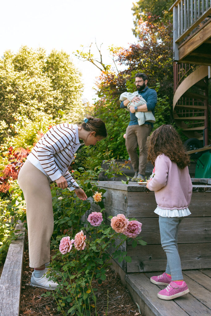 A family of four in their backyard garden during their documentary style at-home newborn photos in Berkeley, California