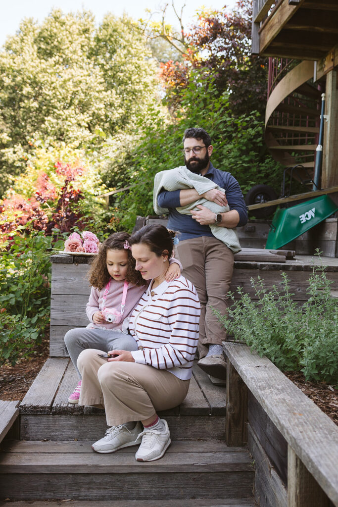 A family of four in their backyard garden during their documentary style at-home newborn photos in Berkeley, California