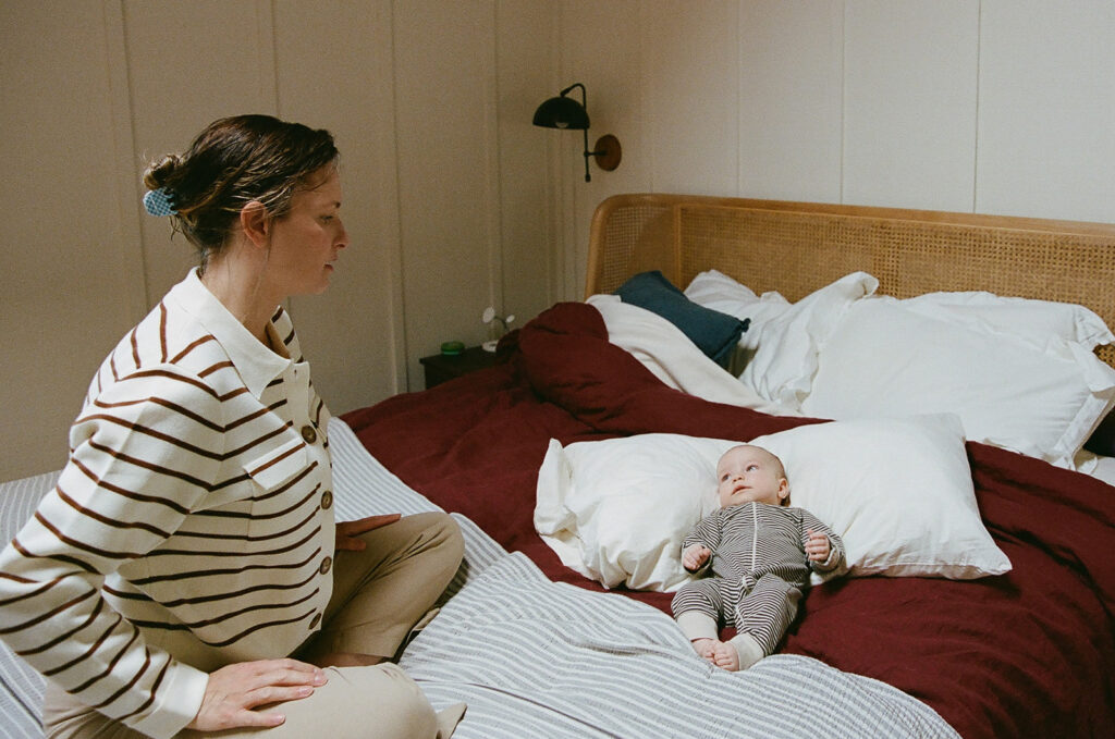 Mother sitting on a bed with her newborn baby