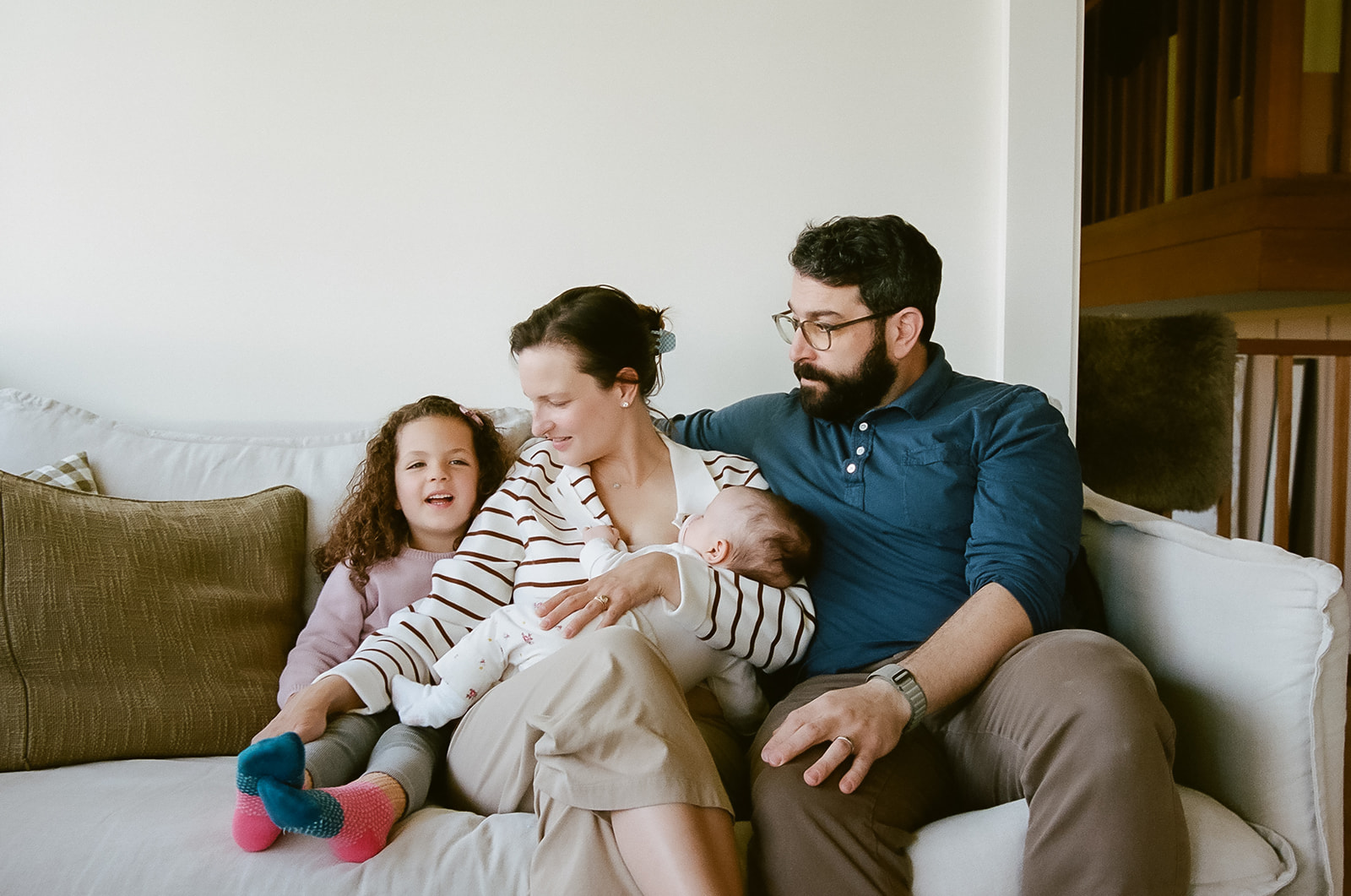 Family of four sitting on their couch during their at-home newborn family photos in Berkeley, California