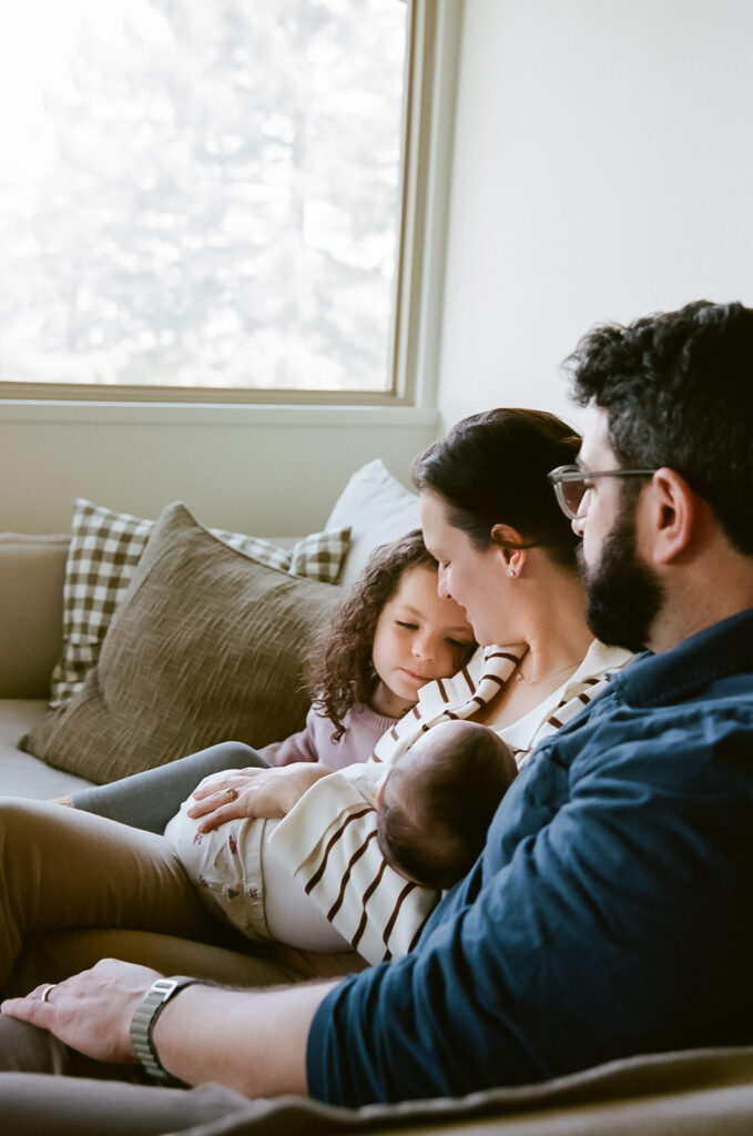 Family of four sitting on the couch together for their at-home Berkeley newborn photos