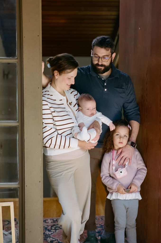 Family of four posing for photos at their front door during the end of their at home newborn photos in Berkeley, California