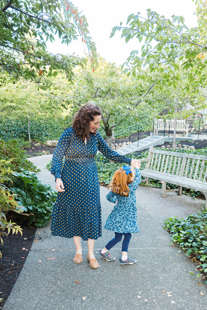 Mother twirling her daughter around while walking at the park