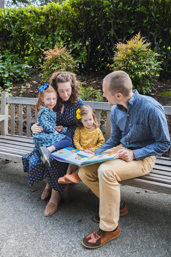 Parents reading their daughters a book at the park