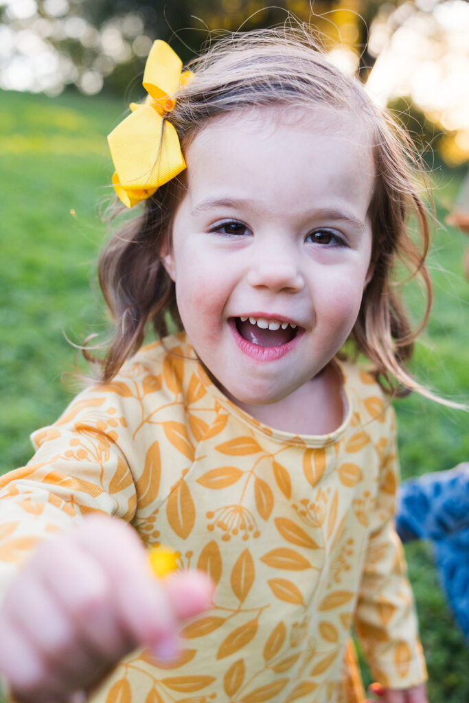 Little girl showing the camera a dandelion that she picked