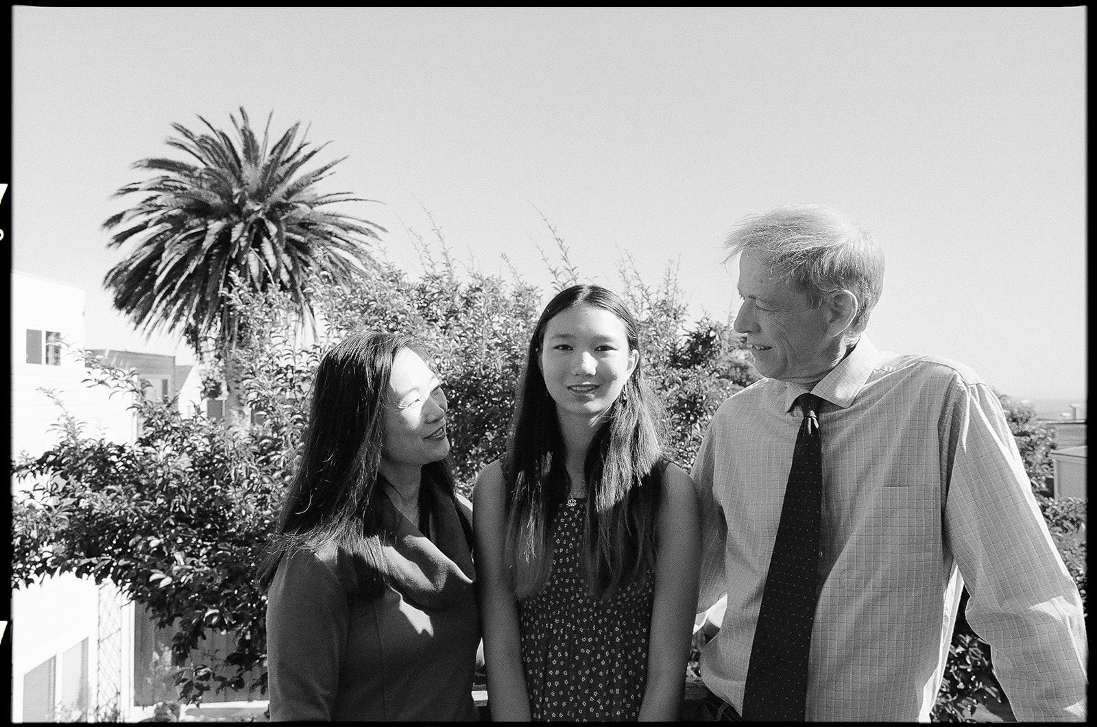 Black and white photo of a family of three posing for their at-home family photos in San Francisco captured on film