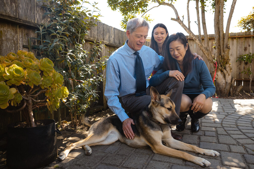 Family of three petting their German Shepard dog