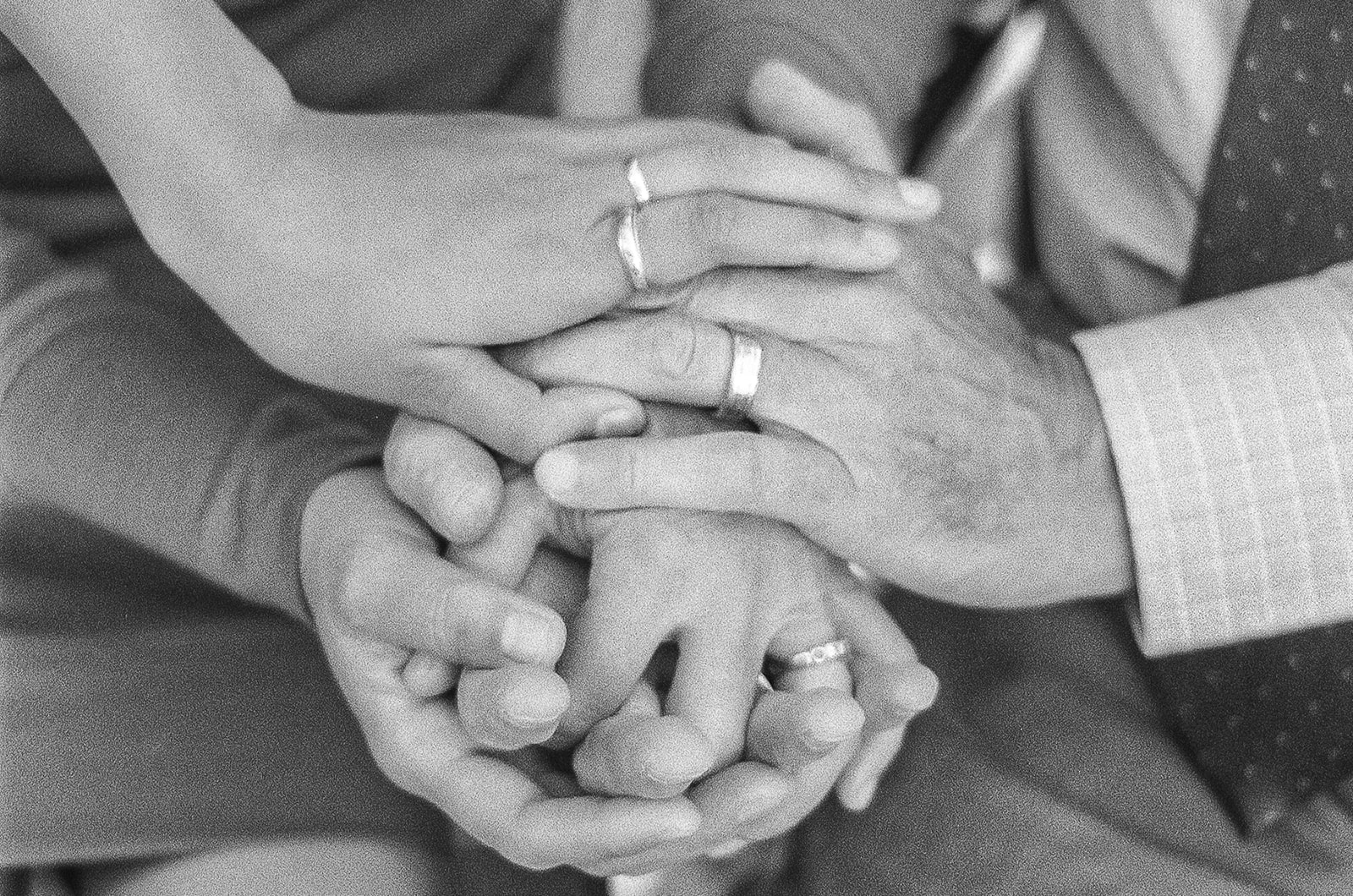 Black and white close up photo of a family of three with their hands on top of each other