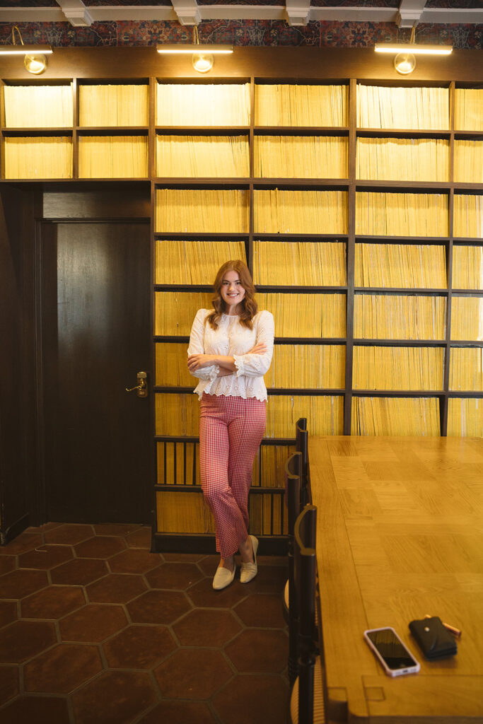 Woman posing in front of a wall of yellow encyclopedia's for her creative Bay Area brand photoshoot at The Graduate Hotel