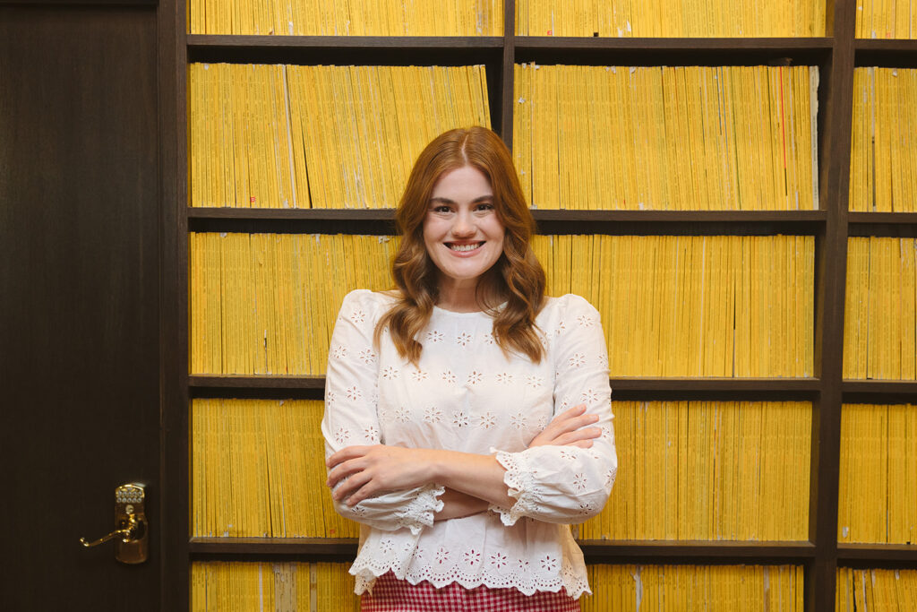 Woman posing in front of a wall of yellow encyclopedia's for her creative Bay Area brand photoshoot at The Graduate Hotel