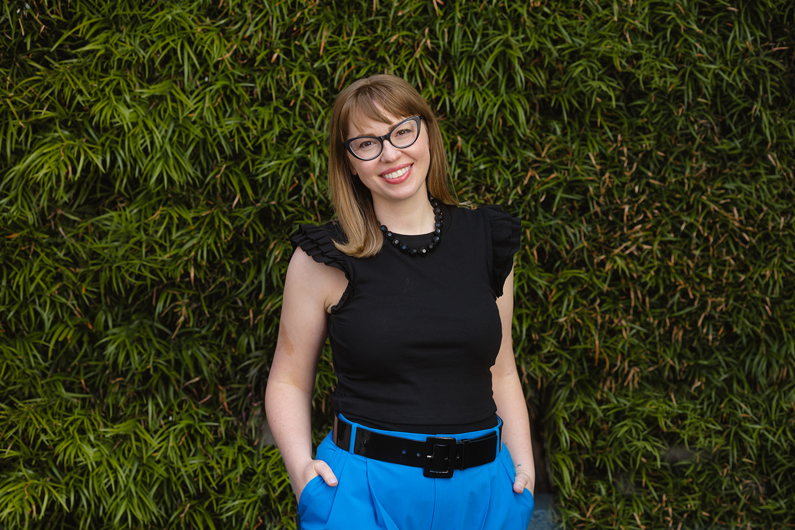 Woman posing in front of a green bush