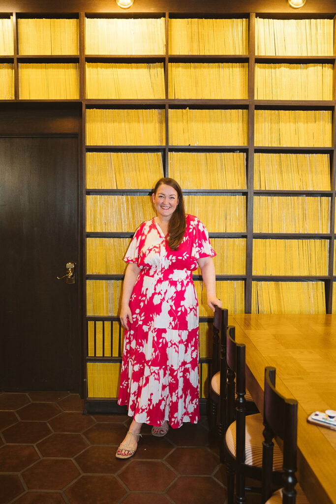 Woman posing in front of a wall of yellow encyclopedia's for her creative Bay Area brand photoshoot at The Graduate Hotel