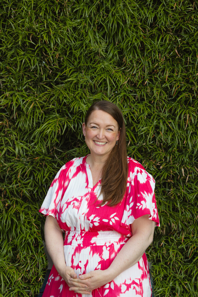 Woman posing in front of a green shrub bush