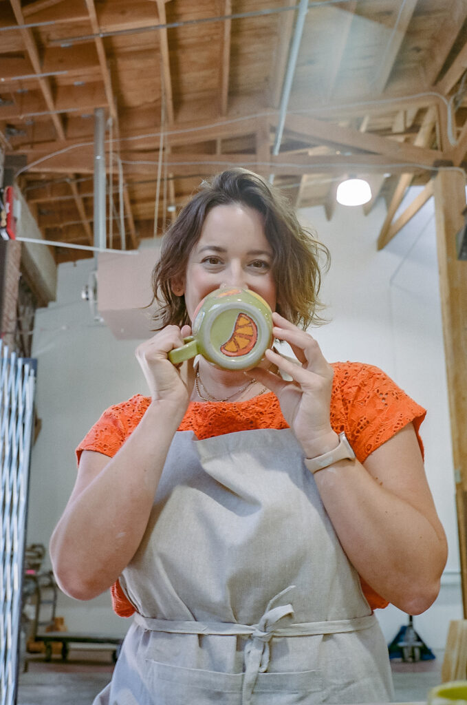 Woman holding up a green mug that she made for her creative film branding photography for The Pottery Studio San Francisco 