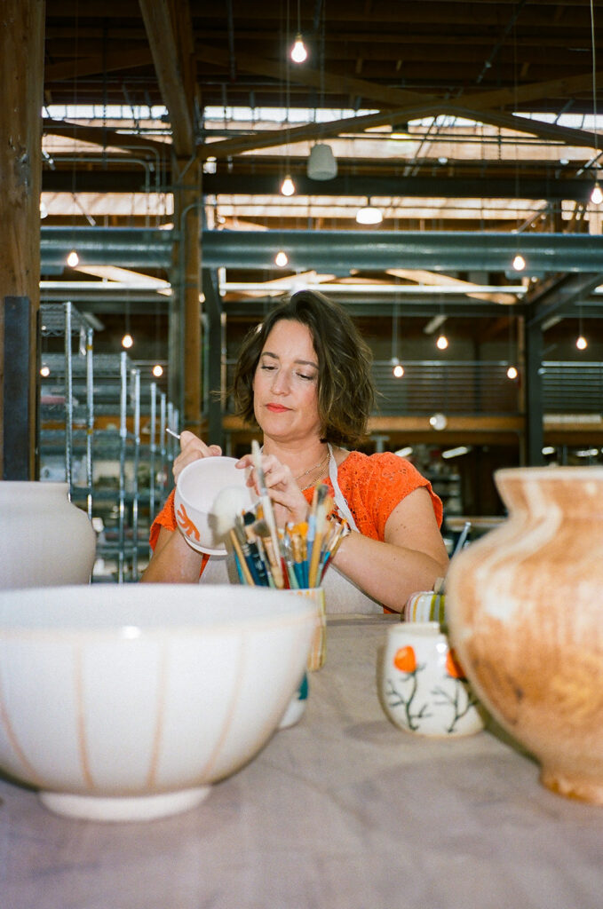 Woman painting some of her pottery during her creative film branding photography for The Pottery Studio San Francisco