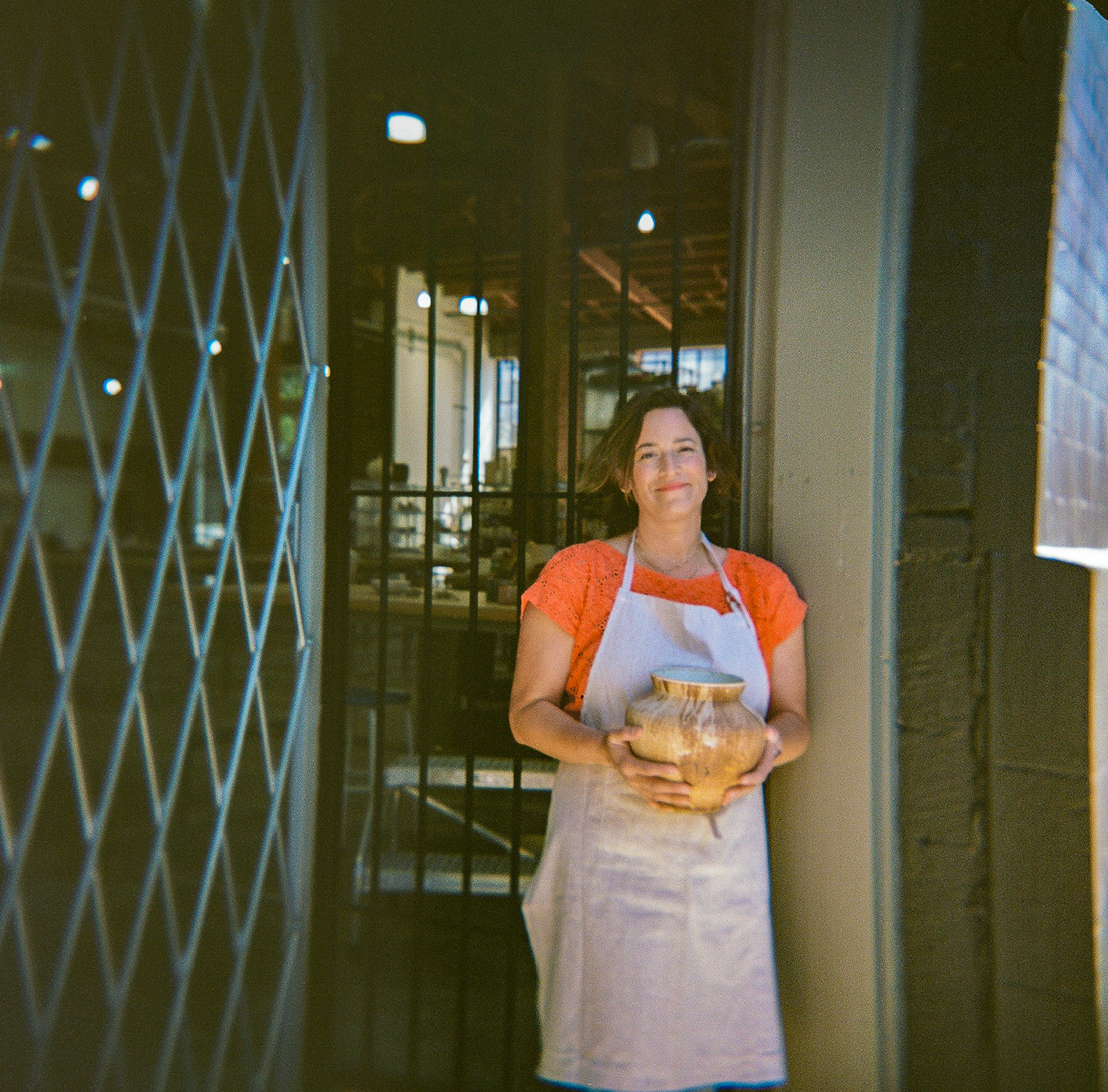 Woman holding a piece of her work up during her creative film branding photography session for The Pottery Studio San Francisco