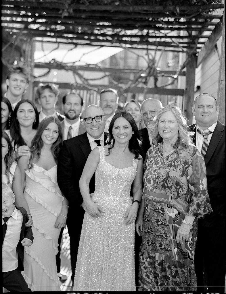 Black and white film photo of a bride and groom posing with their family