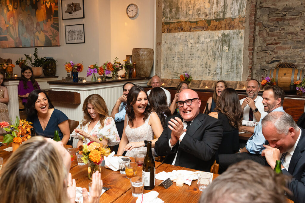 Bride and groom laughing during speeches at their Pizzaiolo wedding reception in Oakland, California