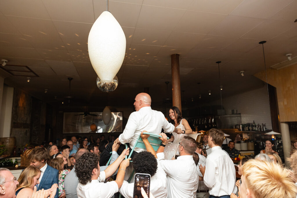 Bride and groom being lifted up onto chairs