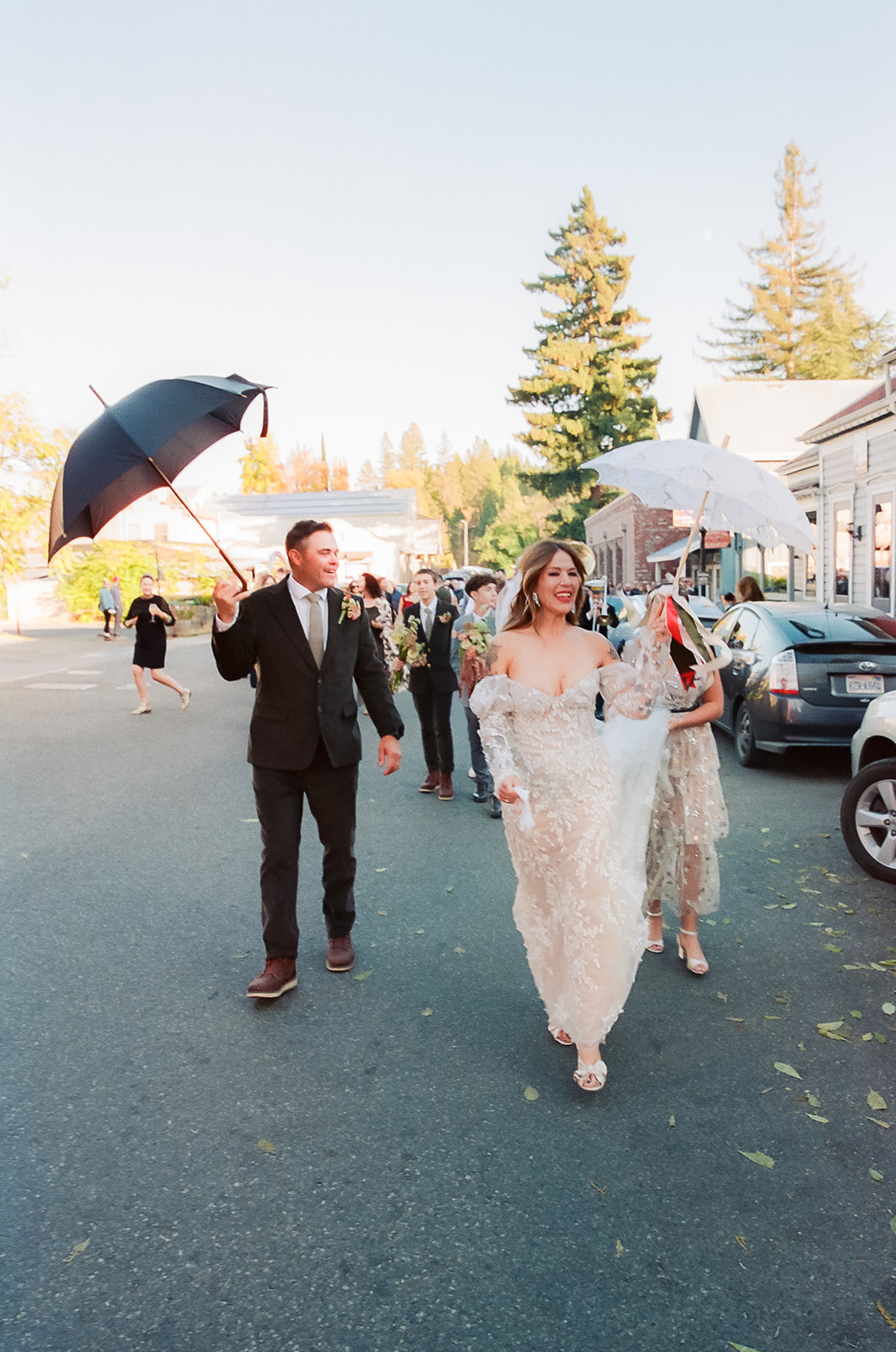 Bride and groom leading marching band processional through Nevada City street