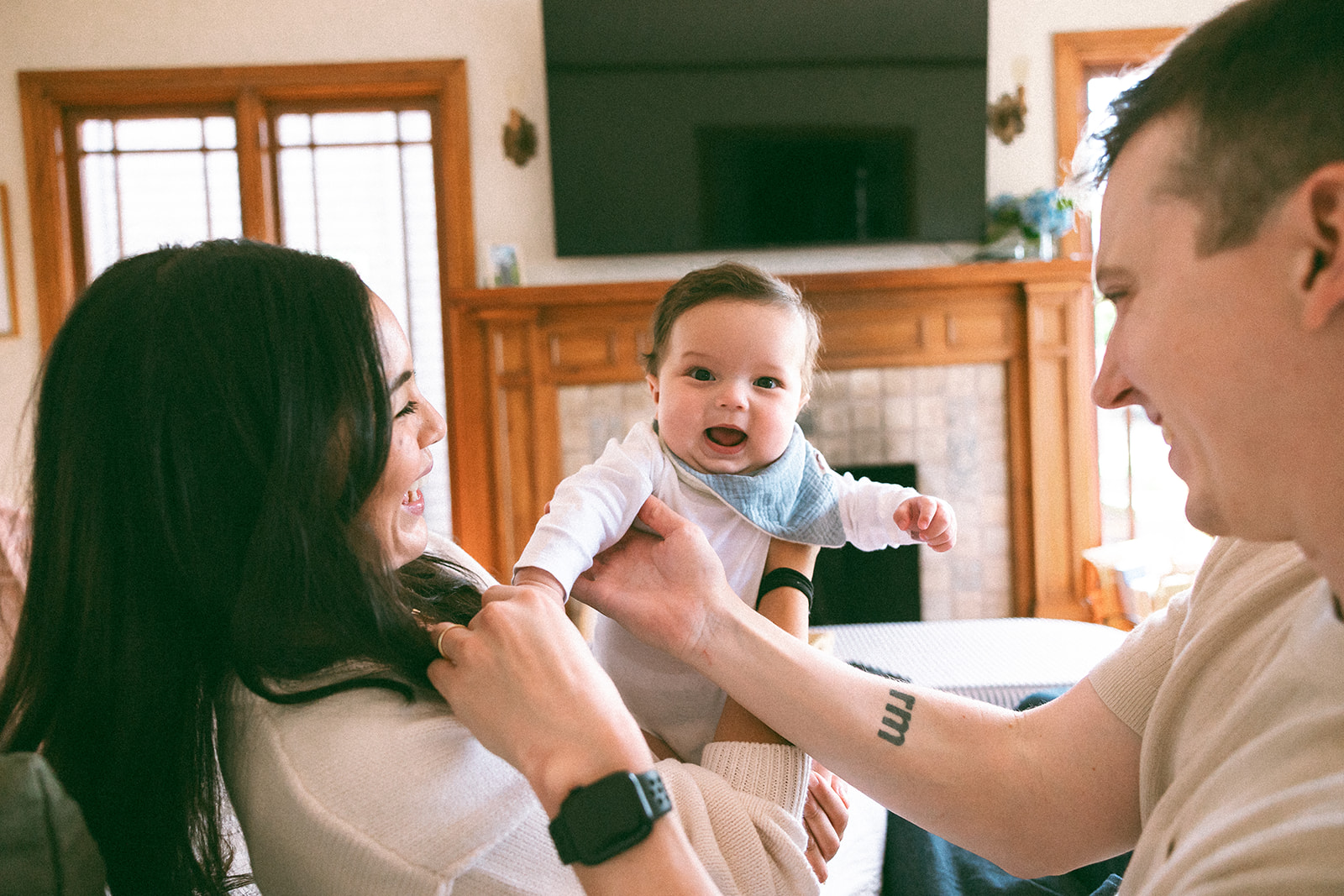 Mother and father being playful with their small baby at home in their living room. 