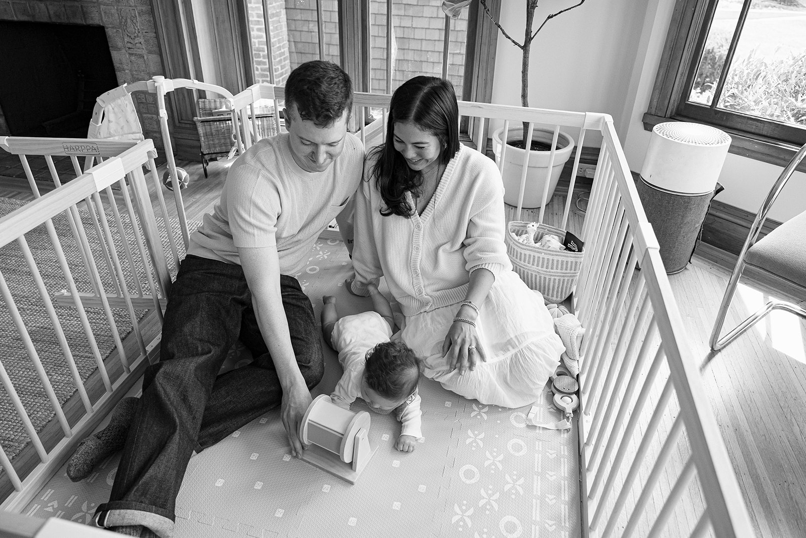 Black and white portrait of a family of three playing on the floor in their living room during their at-home family photos in Oakland, California.