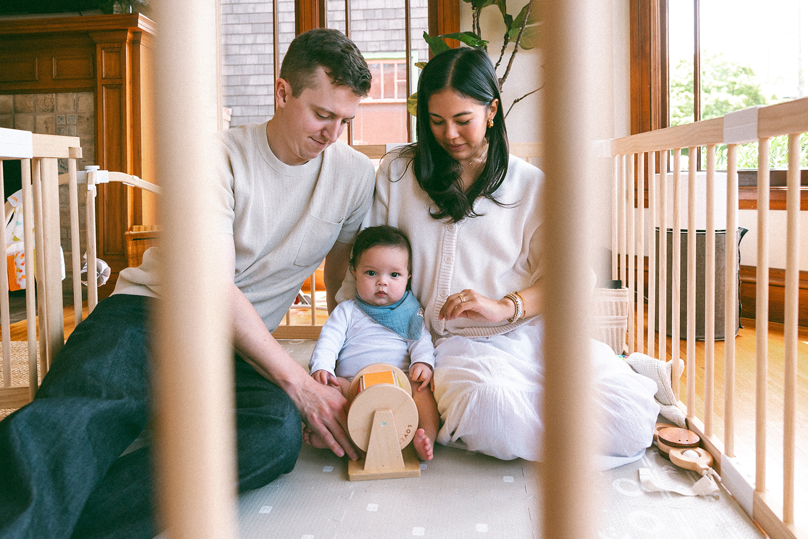 Family of three sitting with their small baby on their living room floor during their documentary style at-home family photos. 