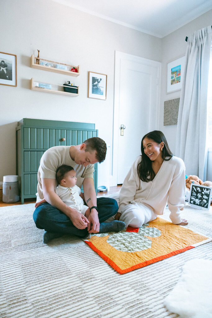Family of three sitting in a nursery for their at-home family photos in Oakland, California.