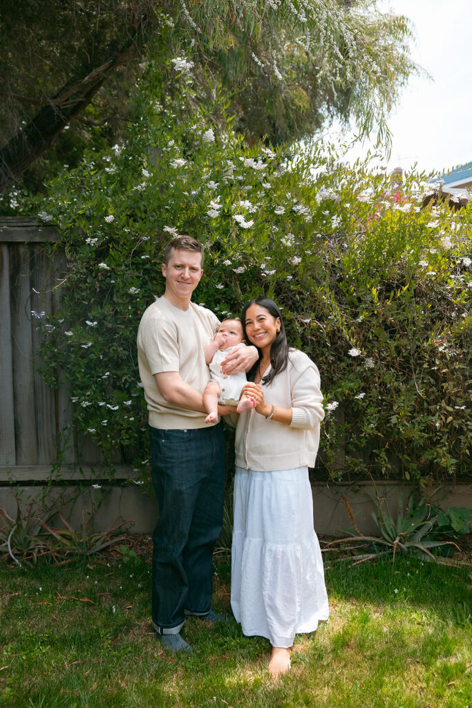 Family of three posing in their backyard for their at-home family photos in Oakland, California. 