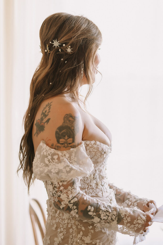 Close up photo of a bride waiting by a window to share a first look with her groom.