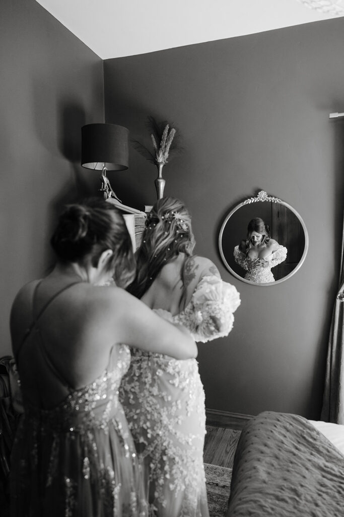 Black and white photo of a bride getting her wedding dress zipped up at Moonrise on Mill Street Inn in Nevada City, California.