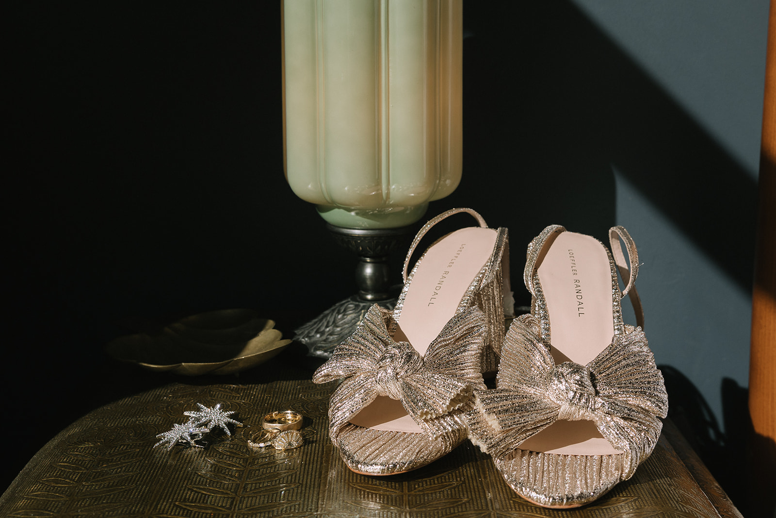 Brides shoes and jewelry styled on a table. 