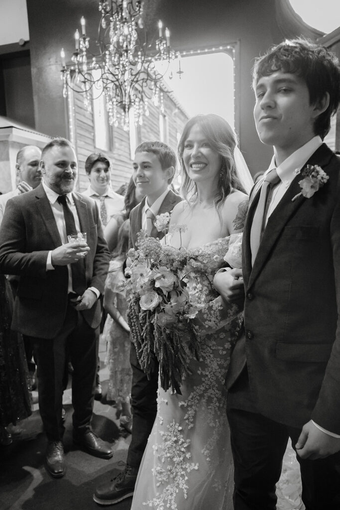 Bride walking down the aisle with her sons in the Upper Gallery at Miners Foundry wedding in Nevada City, California.