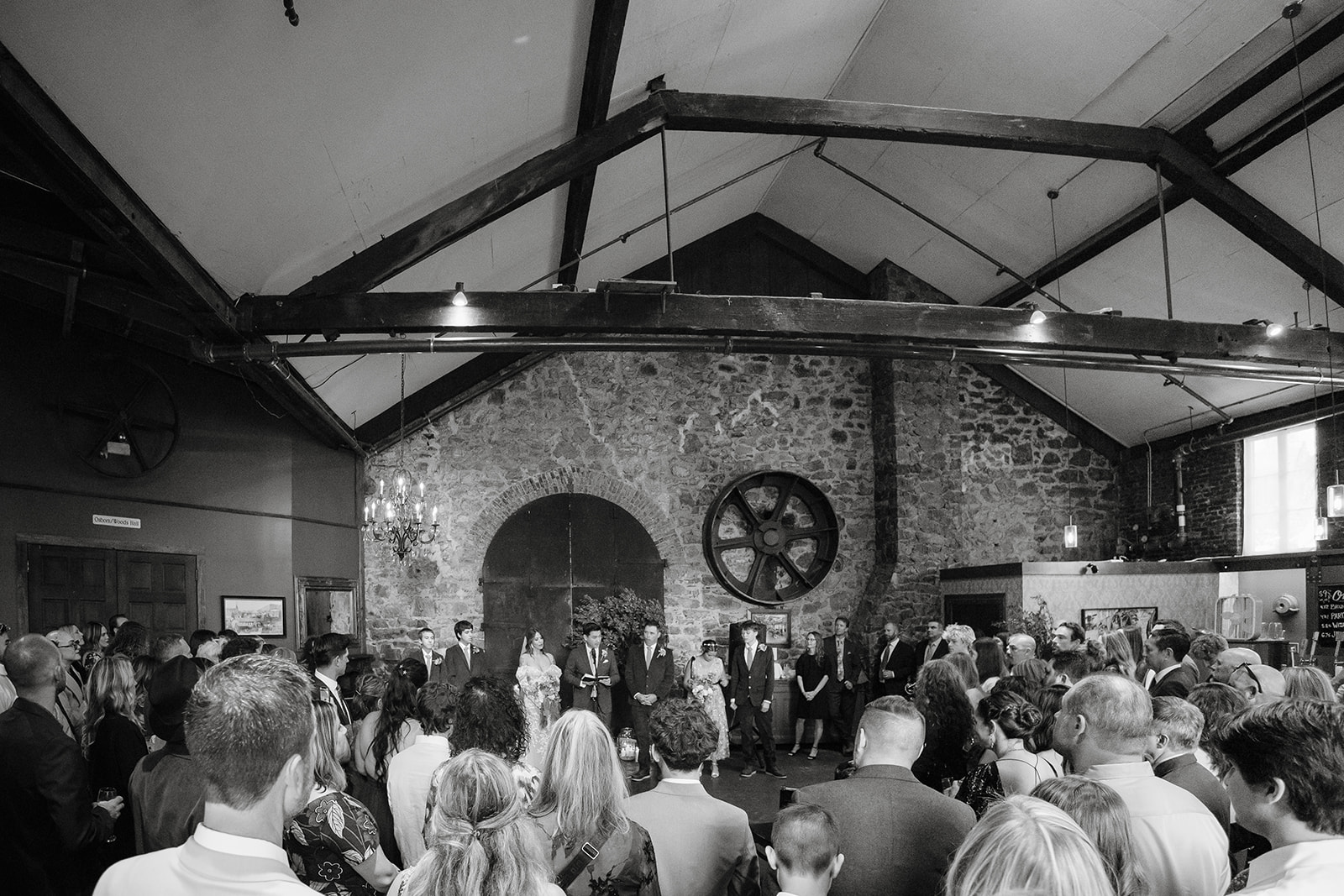Wide view of ceremony with guests gathered in a circle in the Upper Gallery at Miners Foundry wedding in Nevada City, California.