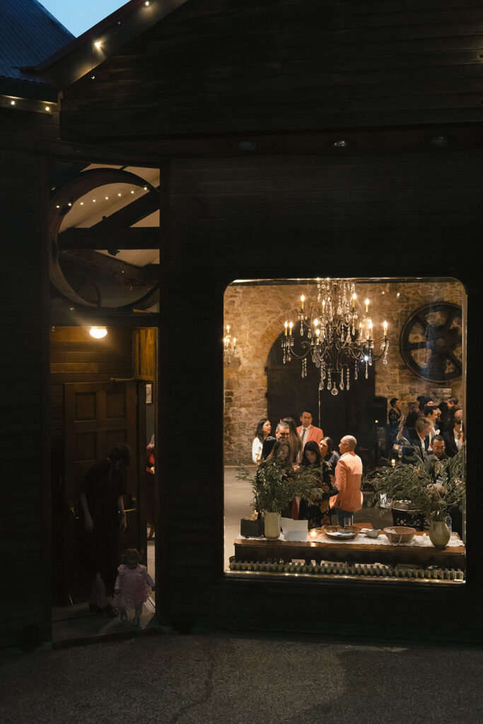 Cocktail hour scene through window showing guests gathering inside Miners Foundry in Nevada City, California.