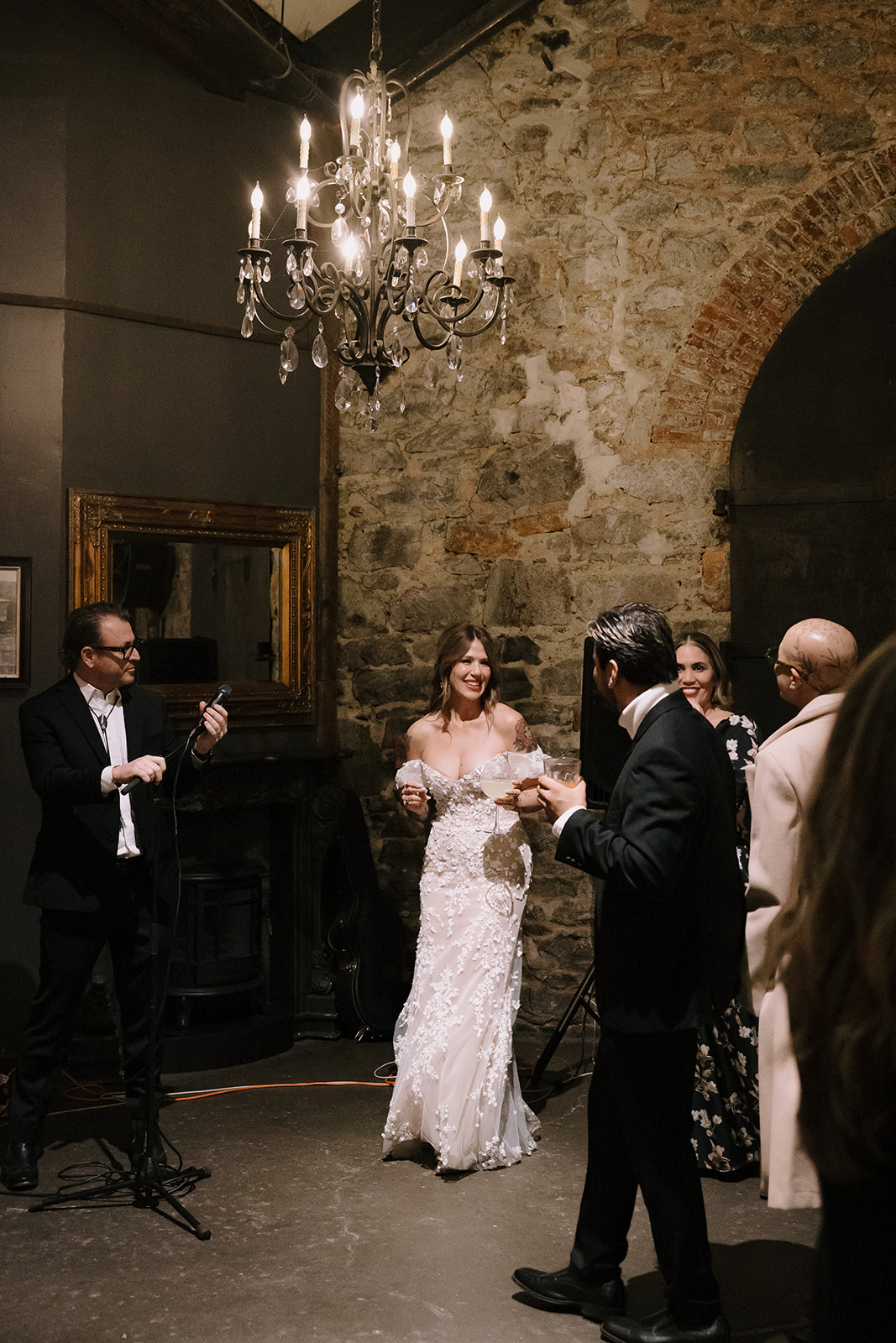 Guests mingling during cocktail hour in the foyer with chandeliers at Miners Foundry wedding in Nevada City, California.