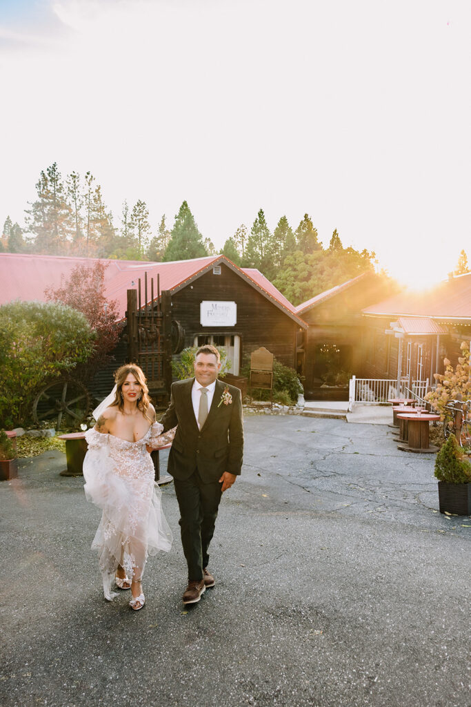 Bride and groom walking toward camera in golden hour light outside Miners Foundry during wedding in Nevada City, California.
