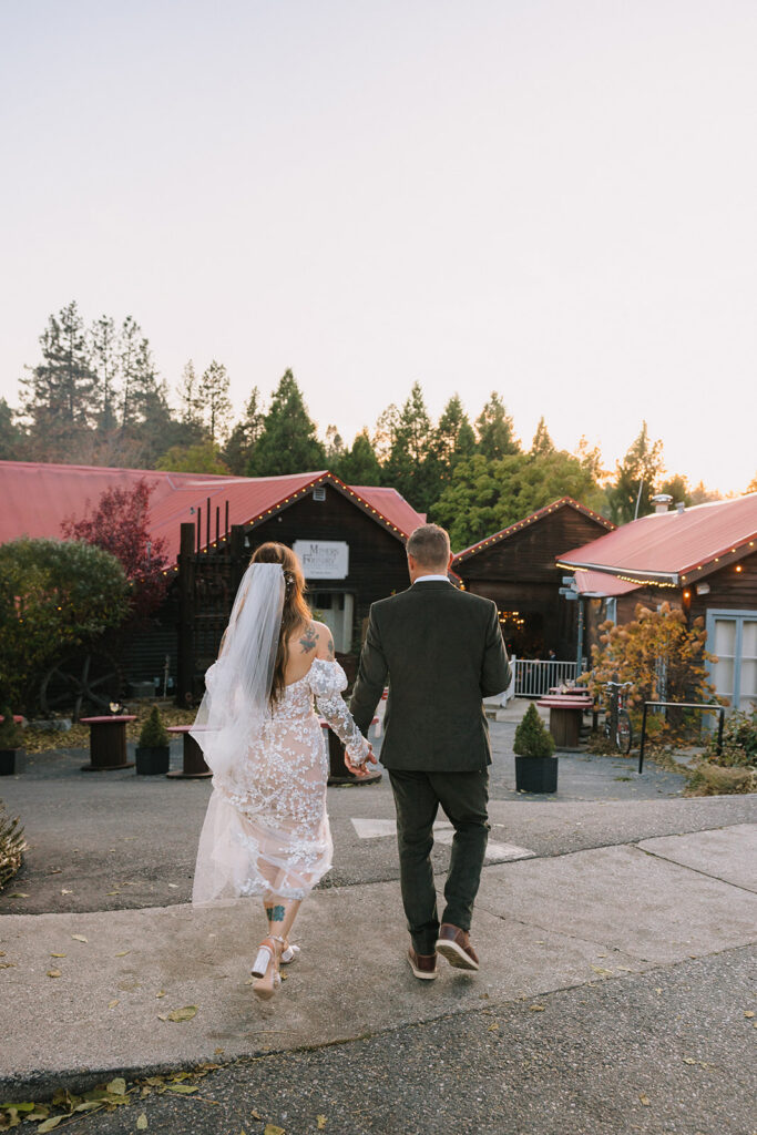 Bride and groom walking away hand in hand toward Miners Foundry during golden hour wedding portraits in Nevada City, California.