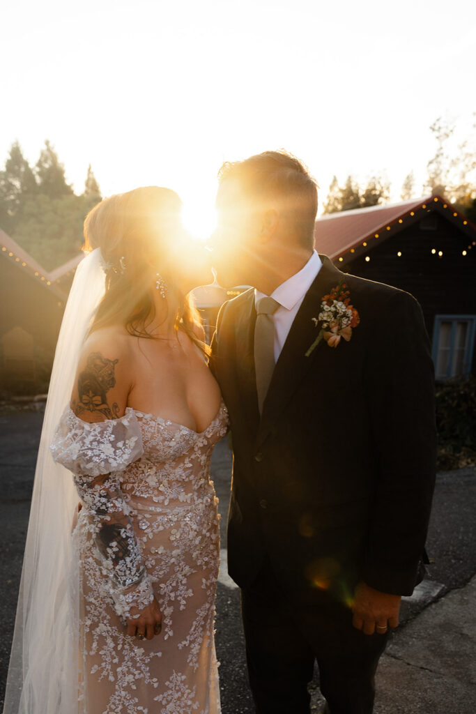 Bride and groom sharing a kiss in warm sunset light during golden hour portraits at Miners Foundry wedding in Nevada City, California.