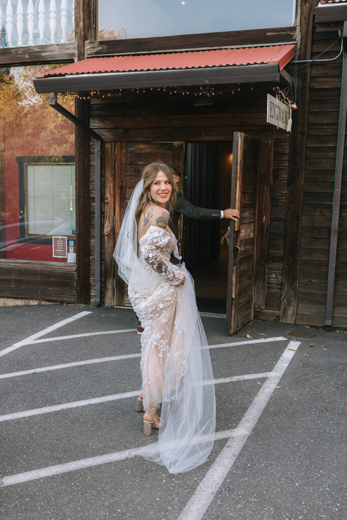 Bride turning back and smiling while entering reception space after marching band processional at Miners Foundry wedding in Nevada City, California.