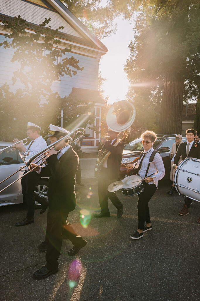 Marching band playing instruments in golden light during wedding processional in Nevada City for Miners Foundry wedding in California.