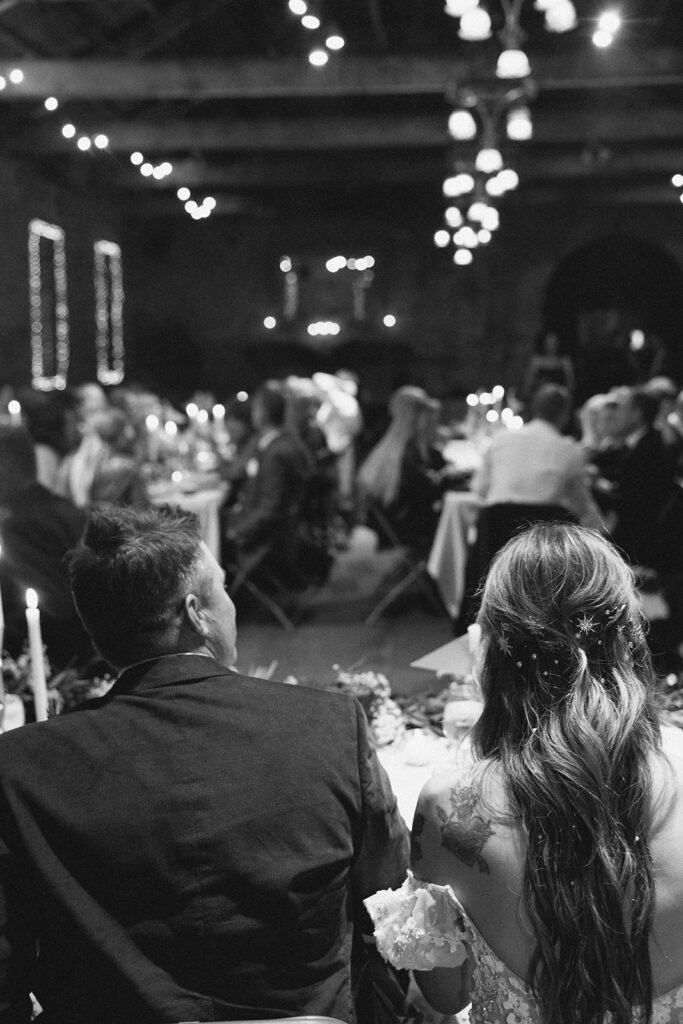Black and white photo of bride and groom seated together during reception at Miners Foundry wedding in Nevada City, California.