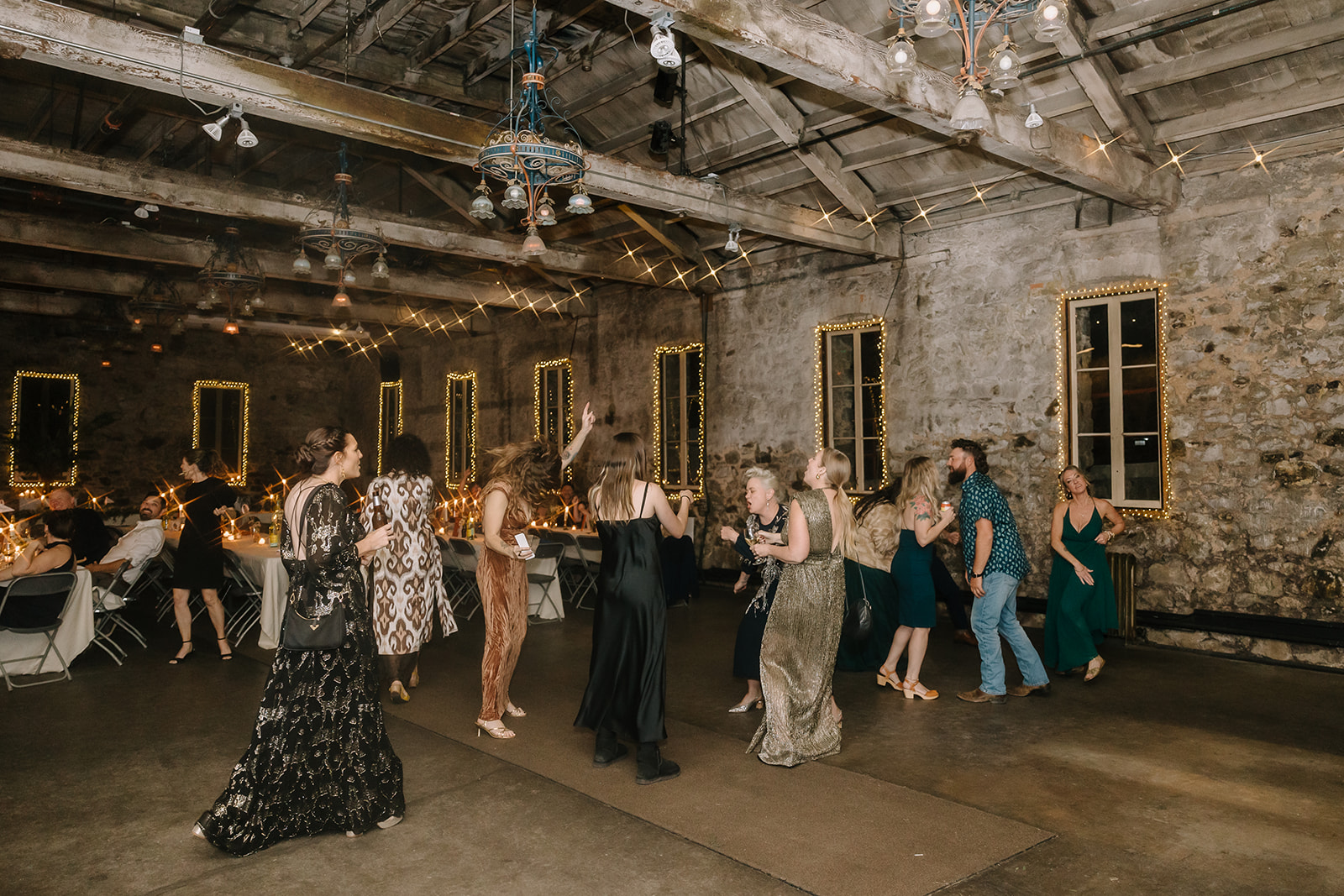 Guests dancing under string lights during reception in Stone Hall at Miners Foundry wedding in Nevada City, California.