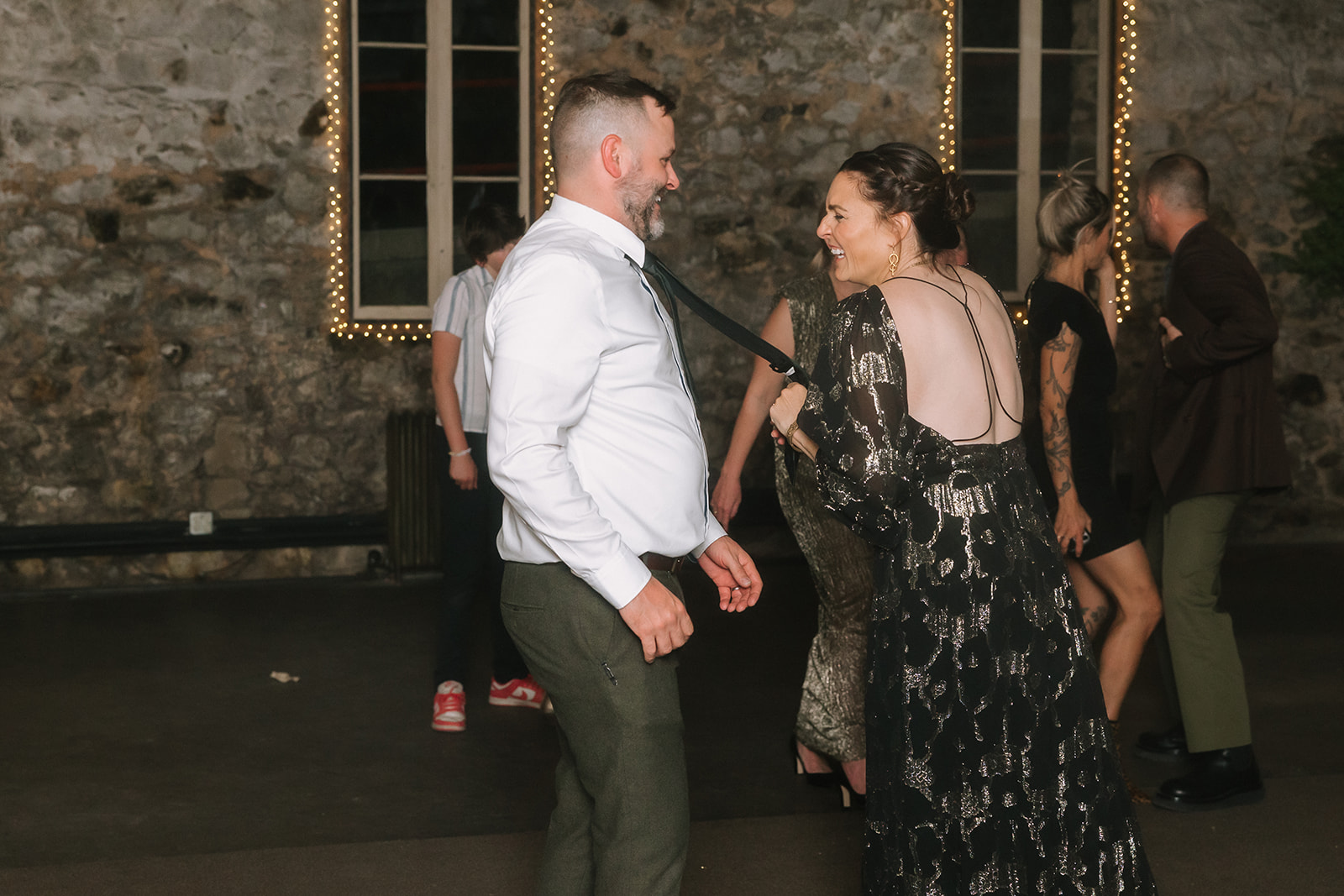 Guests dancing under string lights during reception in Stone Hall at Miners Foundry wedding in Nevada City, California.