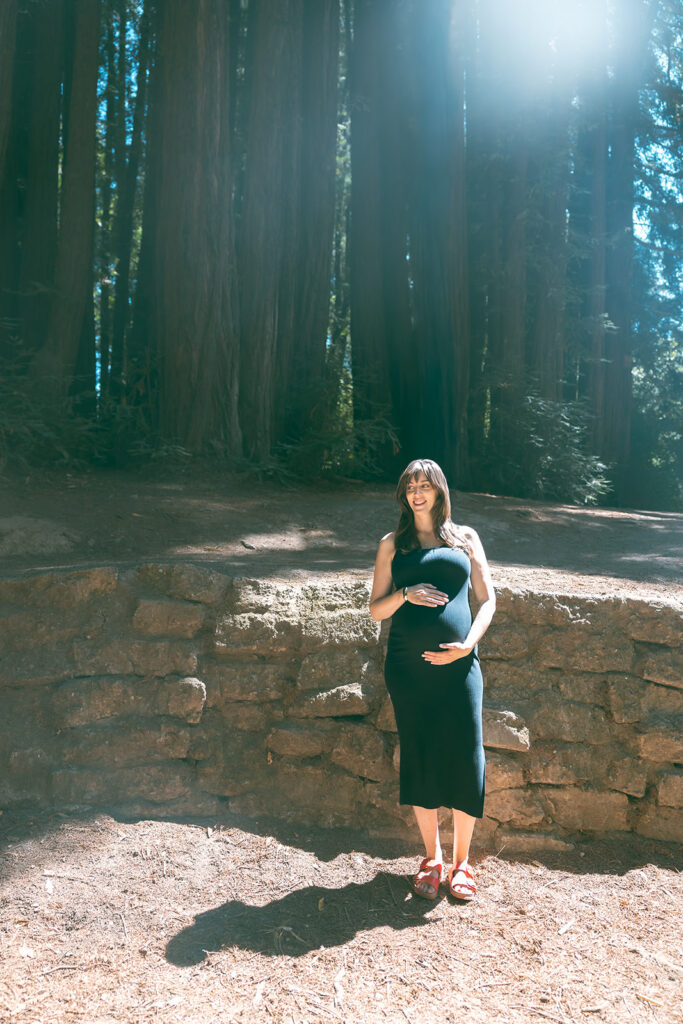 Pregnant mother standing in redwood grove at Old Mill Park in Mill Valley.