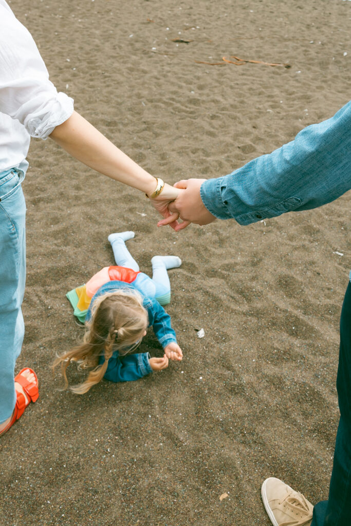 Little girl rolling in the sand on Rodeo Beach.