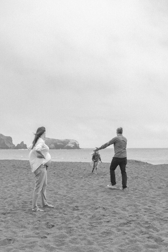 Family of three running along Rodeo Beach in Marin Headlands. 