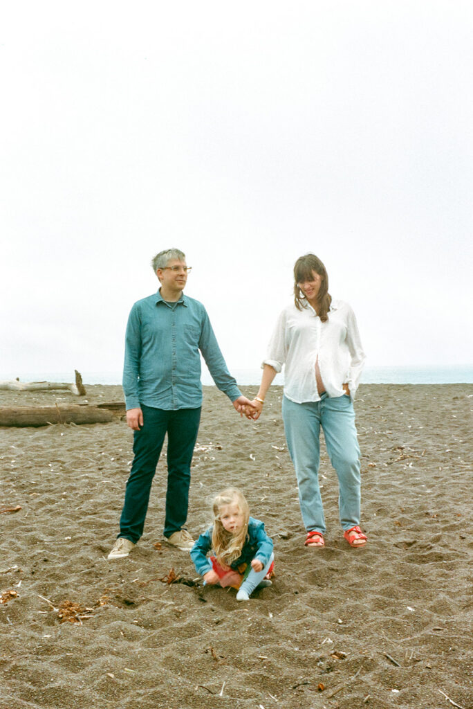 Family maternity portrait at Rodeo Beach with coastal cliffs in Marin County on 35mm film.